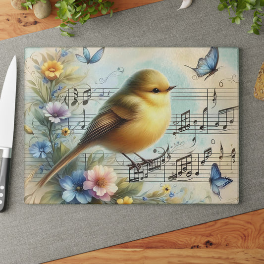 Tabla de cortar de vidrio templado con forma de pájaro rodeada de mariposas, flores y notas musicales.